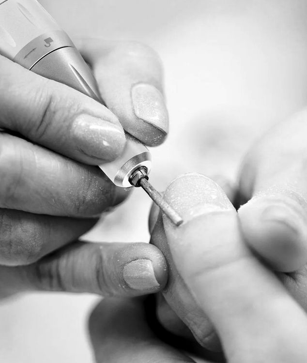 Close-up of electric file work refining the nail surface