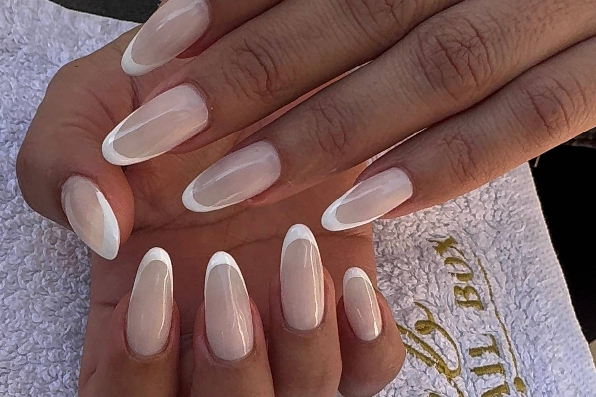 Soft white french tip almond nails on a branded Nail Box towel